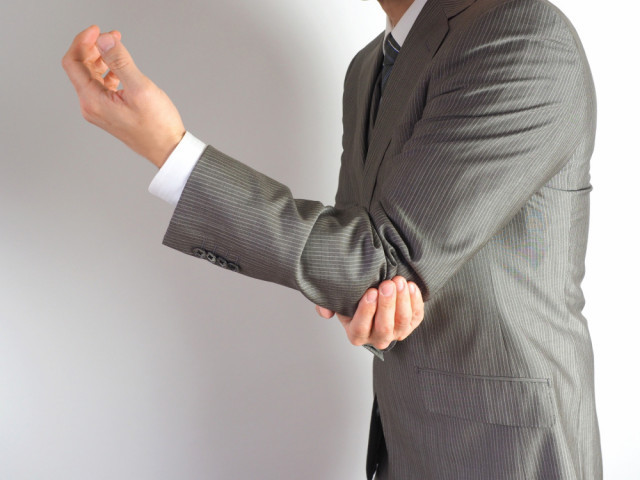 肘を抑える男性の写真